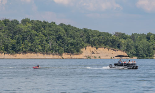 Pontoon boat pulling a child on a tube