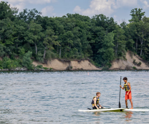 Two kids paddle boarding 