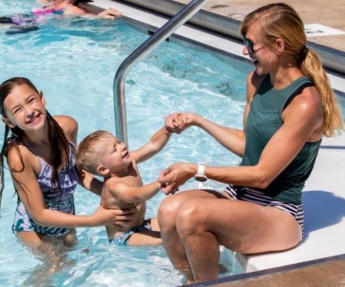 Mother and daughter helping son in pool