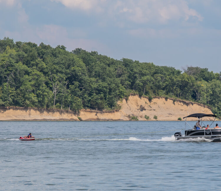 Pontoon boat pulling a child on a tube